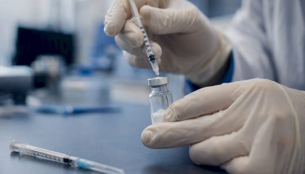 Hands adding solvent to peptide vial